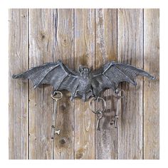 a metal bat shaped key holder on a wooden wall with keys hanging from it's sides