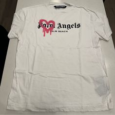 Brand: Palm Angeles Type: T Shirt Style: Spray Heart - Palm Beach Color: White W/ Pink Size: Large Condition: Good, Has Faint Armpit Discoloration. Pink Palm Angels Top, Armpit Discoloration, Angel Shirt, Beach T Shirt, Beach Color, Beach T Shirts, T Shirt Style, Palm Angels, Large White