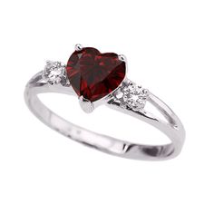 a heart shaped ring with two diamonds on the side and a red stone in the middle