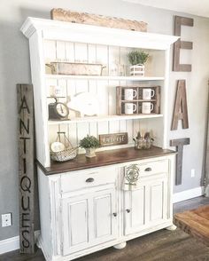 a white hutch with some plants and other items on it's top shelf