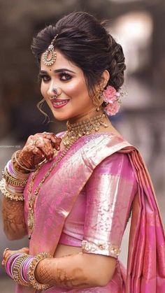 a woman in a pink sari and gold jewelry is posing for the camera with her hands on her chest