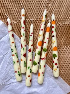 four candles with autumn designs on them sitting on a piece of wax paper next to some scissors