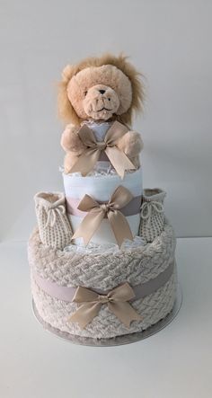 a teddy bear is sitting on top of a diaper cake with bows and ribbons