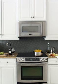 a stainless steel stove and microwave in a kitchen with white cabinets, granite counter tops