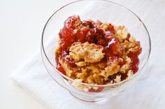 a glass bowl filled with crumbled food on top of a white table cloth