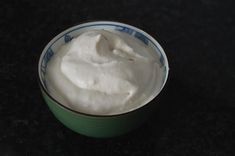 a green bowl filled with white cream on top of a black counter