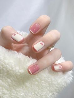 a woman's hand with pink and white manicures on it, while she is wearing a sweater