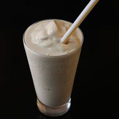 a drink with whipped cream and a straw sticking out of it's top, on a black surface