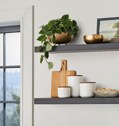 some shelves with bowls and plates on them next to a potted plant in a window sill