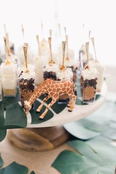 a giraffe is standing on a plate with desserts in front of it