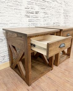 a wooden table with two drawers in front of a brick wall and wood flooring