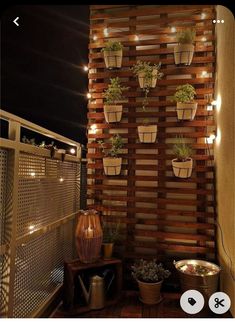 a wooden wall with potted plants on it and lights hanging from the top one