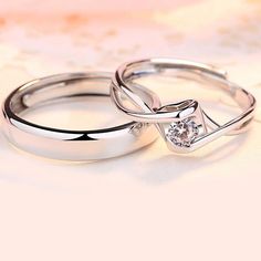 two wedding rings sitting on top of each other with a diamond in the middle,