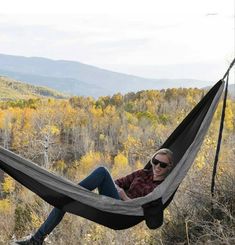 a man sitting in a hammock on top of a hill