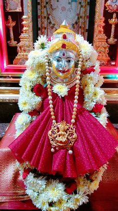 the statue is decorated with flowers and pearls on it's head, as well as a mask