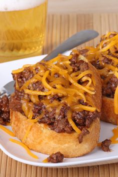 two chili cheese breads on a plate with a glass of beer