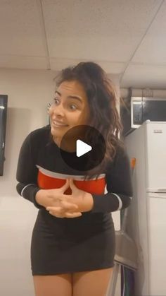 a woman standing in front of a refrigerator with her hands on her hips and looking at the camera