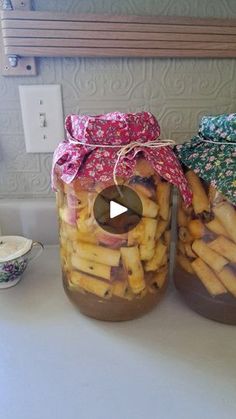 two jars filled with french fries sitting on top of a counter next to each other