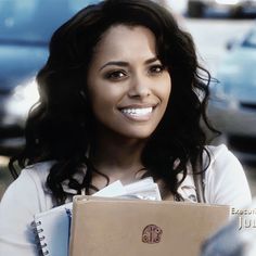 a woman is smiling while holding a folder