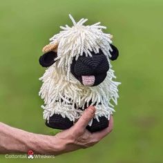 a hand holding a small black and white stuffed sheep in it's right hand