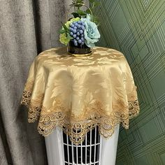 a birdcage with some flowers on top of it and a curtain in the background