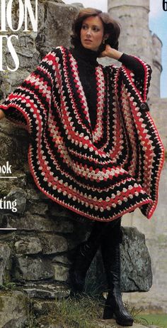 a woman in black and red crocheted shawl leaning against a stone wall