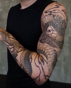 a man with tattoos on his arm holding a cell phone