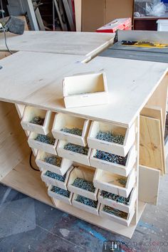 an unfinished workbench with many drawers and tools in the drawer area on the table