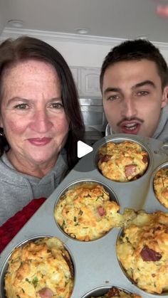 a man and woman are holding up a muffin tray with several muffins in it