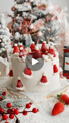 a white cake topped with strawberries on top of a table next to a christmas tree