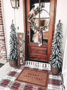 the front door is decorated for christmas with evergreens and pine cones on the mat