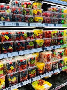 plastic containers filled with different types of fruit on display in a grocery store's produce section