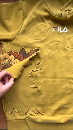 someone is cutting out the letters on a yellow shirt that has been torn off with scissors