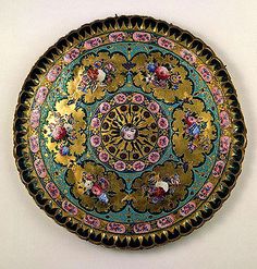 an ornately decorated plate hanging on the wall in front of a white wall,