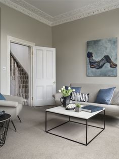 a living room filled with furniture and a painting on the wall above it's door