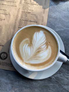 a cappuccino with a feather on it sits next to a menu for the restaurant