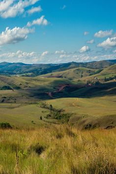 an open field with hills and clouds in the background