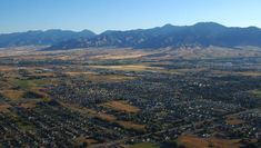 an aerial view of a small town in the middle of a large valley with mountains in the background