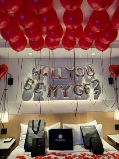 red balloons are hanging from the ceiling above a bed with white sheets and pillows on it