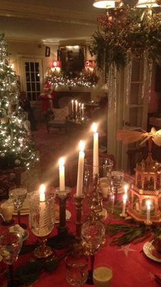 a dining room table is set with candles and dishes for christmas dinner guests can be seen in the background