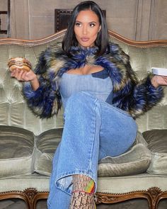 a woman sitting on a couch eating a doughnut and holding a cup in her hand