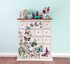 a dresser with butterflies painted on the drawers and vases sitting on top of it