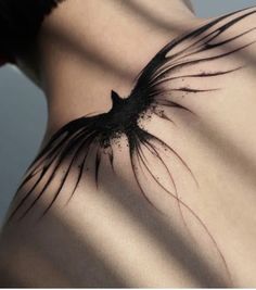 the back of a woman's shoulder with a bird tattoo on it