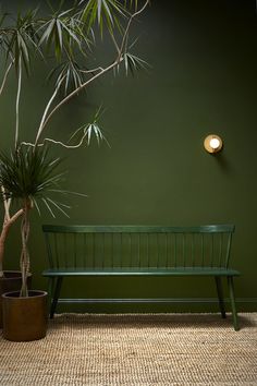 a green bench sitting next to a potted plant