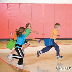 three children running on a basketball court with blocks in their hands and one holding a bag