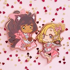 two anime pin badges sitting next to each other on a pink background with confetti sprinkles