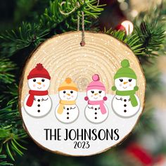 a christmas ornament with three snowmen hanging on a tree branch in the shape of a circle