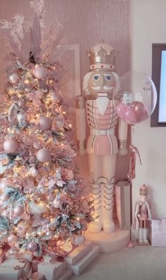 a pink christmas tree with an inflatable nutcracker next to it