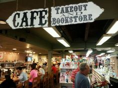 the inside of a bookstore with people sitting at tables and standing in front of it