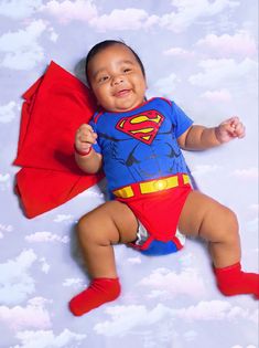 a baby in a superman costume laying on the ground